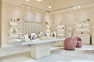 Interior of a high end store with 'Haus of URB' branding, featuring white furniture and decor.